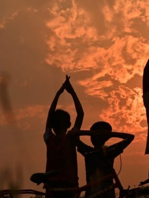 silhouette of 3 person standing beside bicycle during sunset