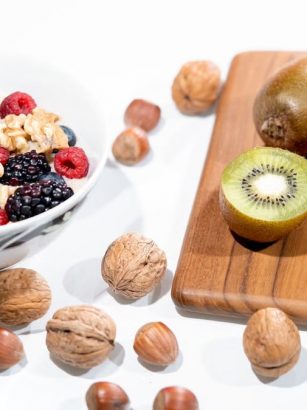 A vibrant bowl of mixed berries, walnuts, and kiwi on a cutting board. Perfect for a healthy breakfast.