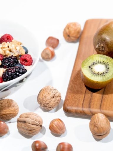 A vibrant bowl of mixed berries, walnuts, and kiwi on a cutting board. Perfect for a healthy breakfast.