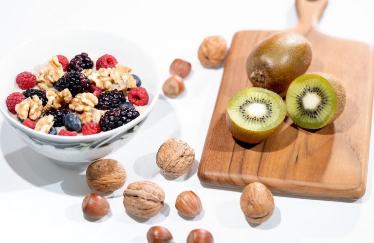A vibrant bowl of mixed berries, walnuts, and kiwi on a cutting board. Perfect for a healthy breakfast.