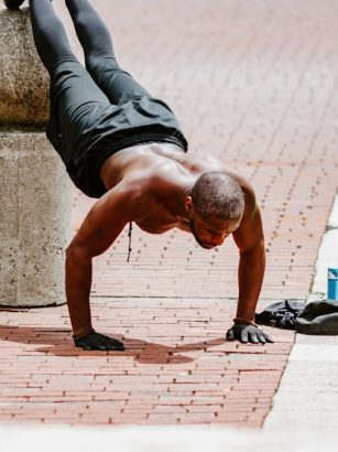 man in black tank top and black shorts lying on brown concrete floor during daytime