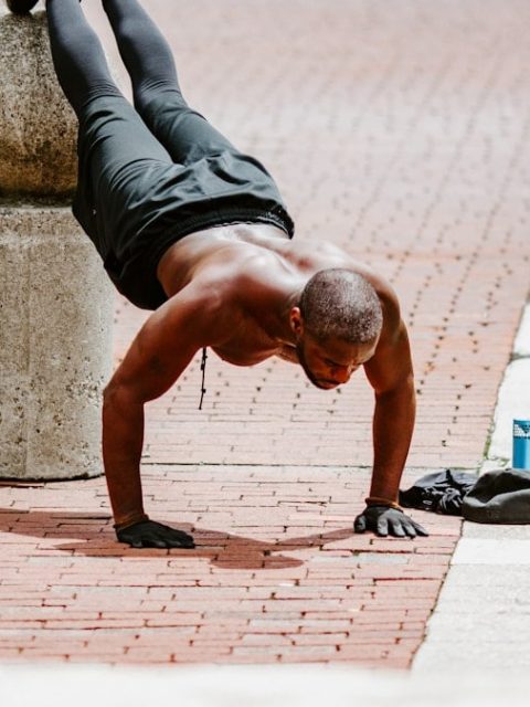 man in black tank top and black shorts lying on brown concrete floor during daytime